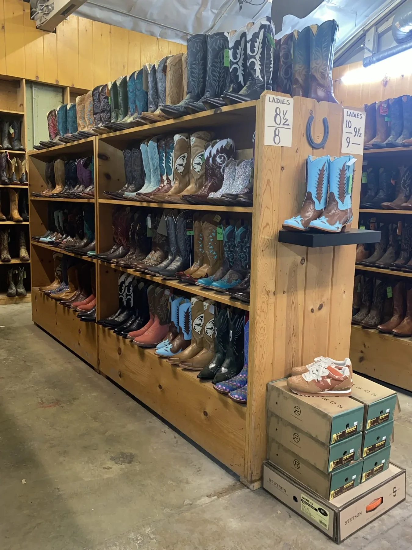 Colorful cowgirl boots arranged by style on wooden shelves
