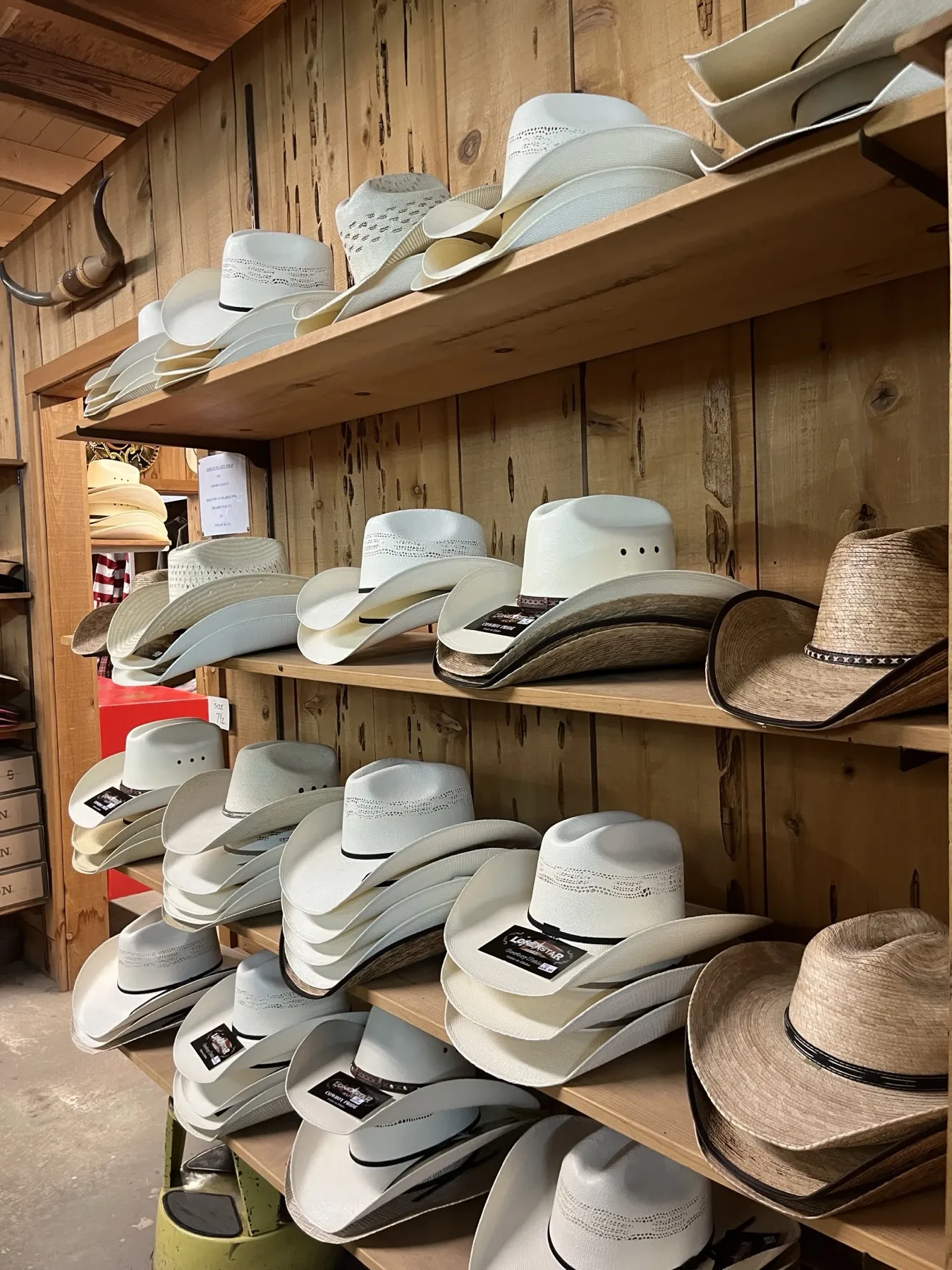 Straw and felt cowboy hats displayed on wooden shelves